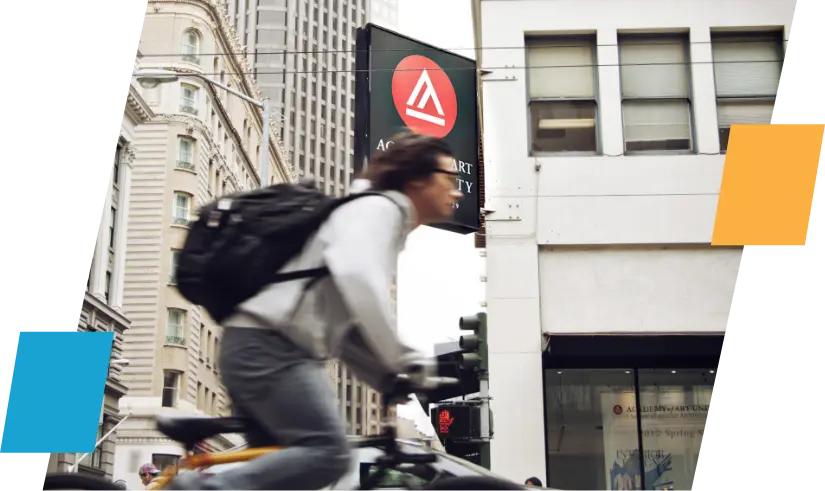 Student riding bike past Academy building